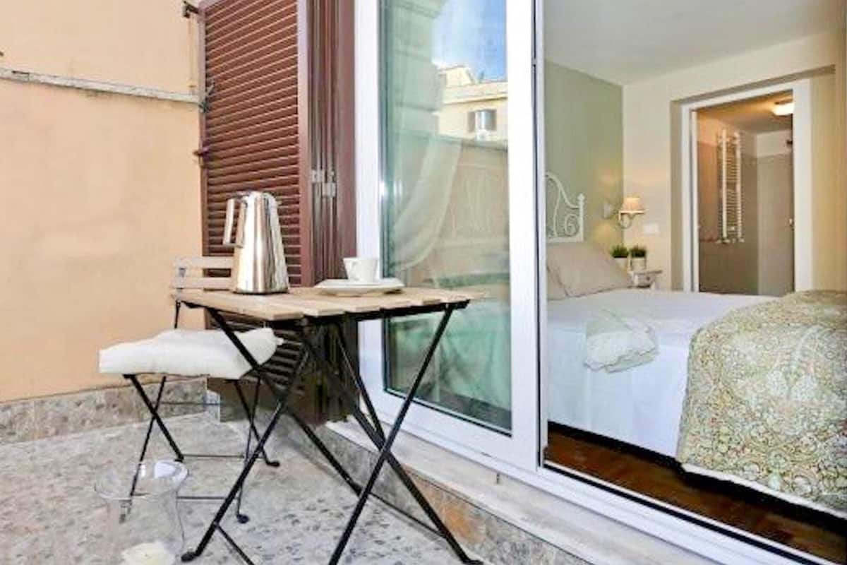 A small balcony with a table, a chair, and a kettle.