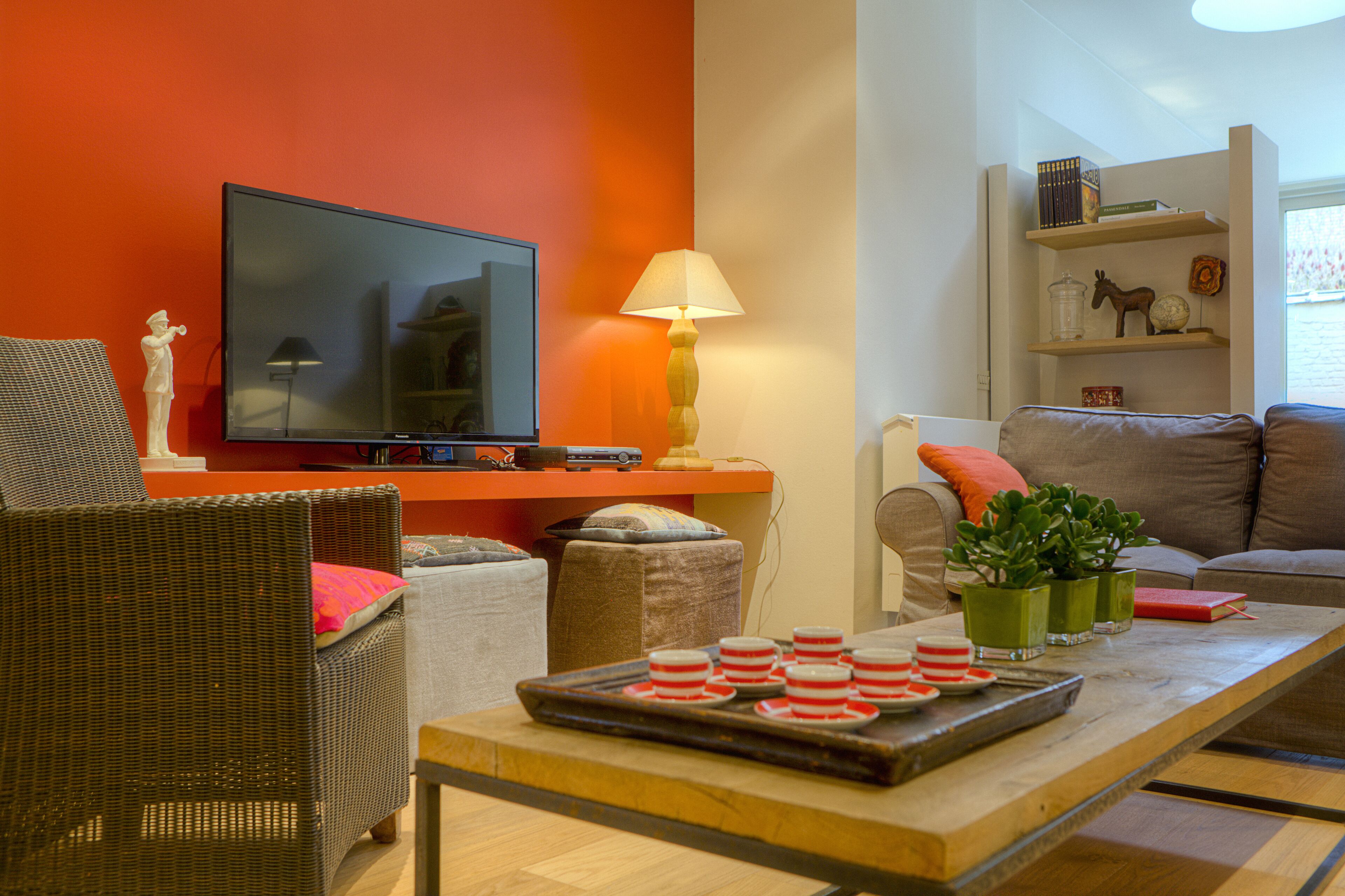 Een woonkamer met een televisie, bank, salontafel en decoratieve objecten.