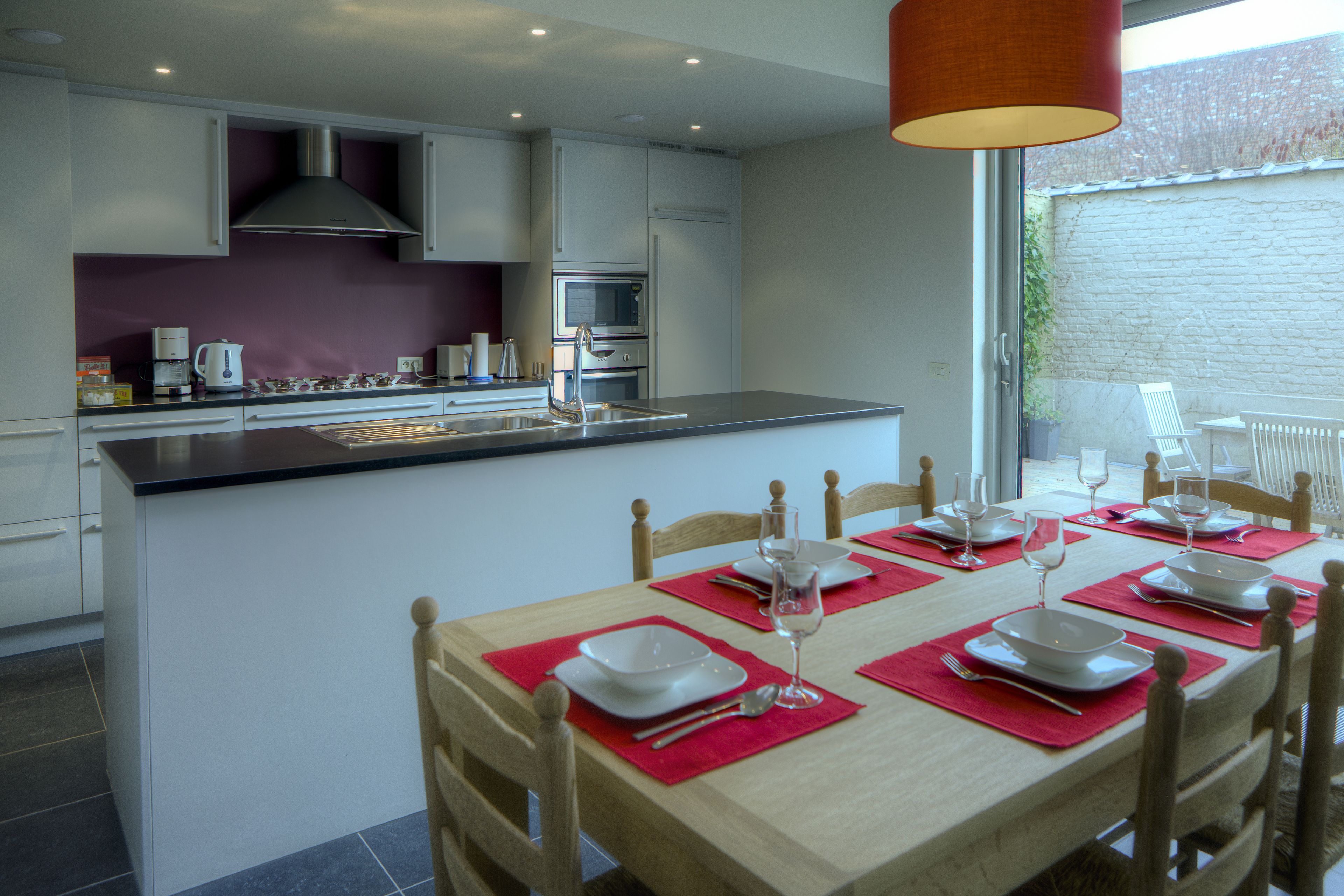 A modern kitchen with white cabinets, a stainless steel range hood, and a built-in microwave.