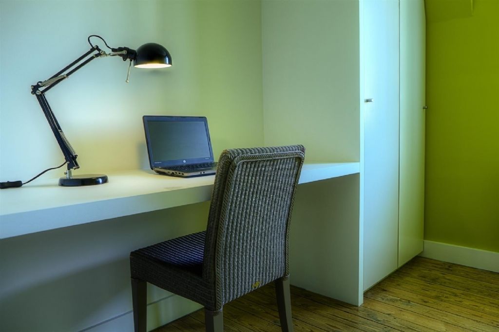 Um espaço de trabalho com um laptop, uma lâmpada de mesa e uma cadeira.