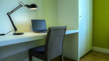 Um espaço de trabalho com um laptop, uma lâmpada de mesa e uma cadeira.