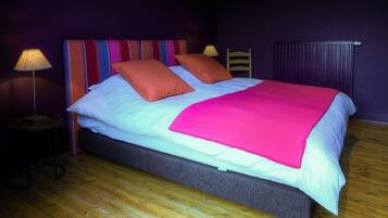 A bed with a colorful striped headboard, two pillows, and a bright pink blanket.