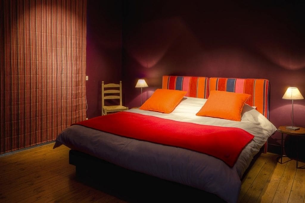 Une chambre d’hôtel avec un grand lit, deux lampes de chevet, une chaise en bois et un rideau à rayures.