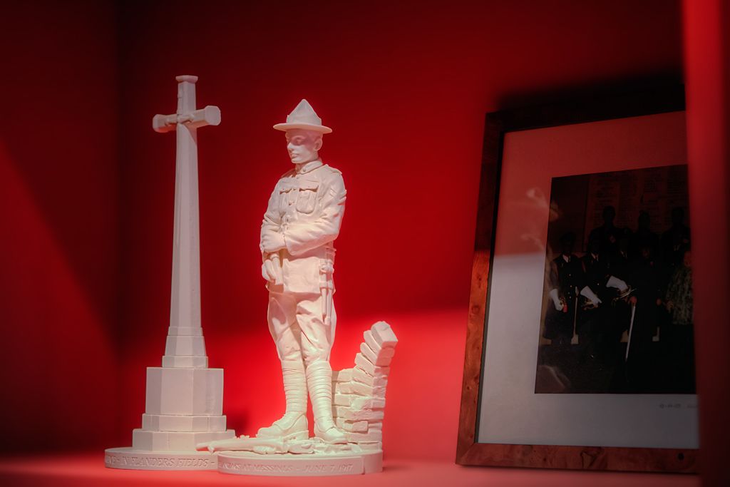 A white statue of a soldier with a cross, standing next to a monument.