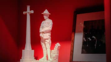 A white statue of a soldier with a cross, standing next to a monument.
