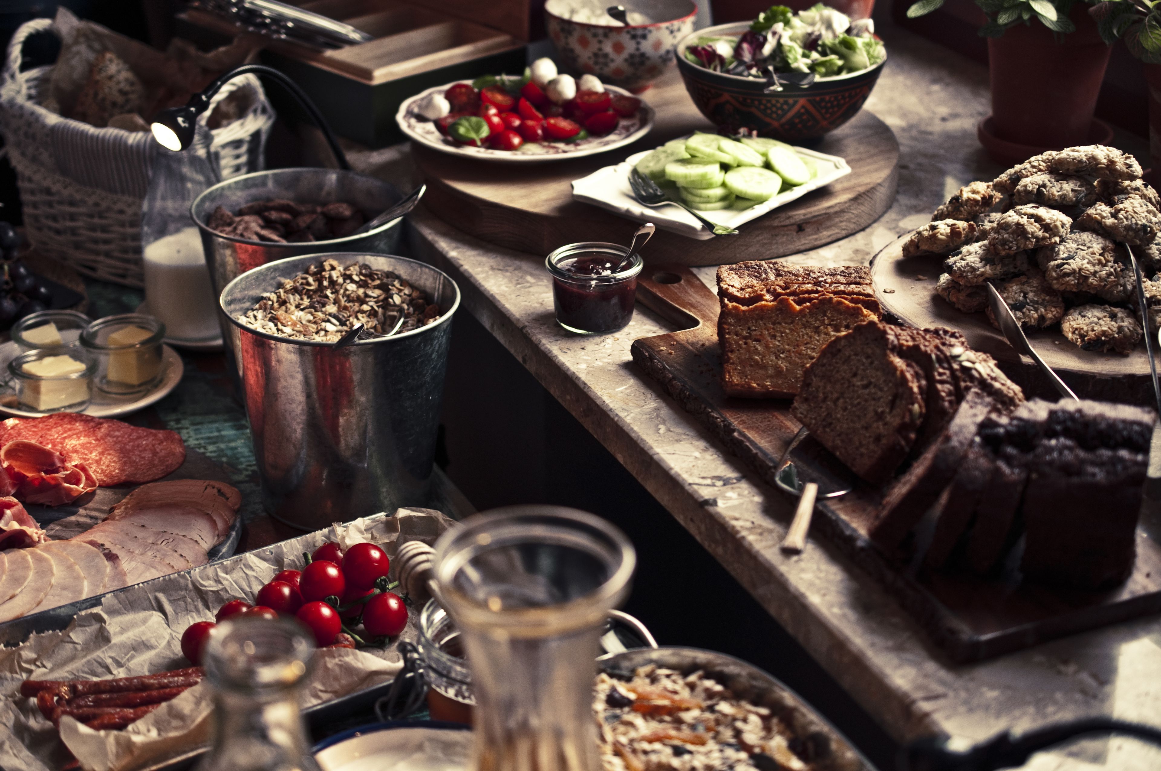 Une variété d’aliments sont disposés sur une table en bois, notamment du pain, du fromage et des tomates.