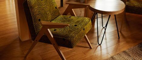 A chair with a geometric pattern, a round wooden table, and wooden flooring.