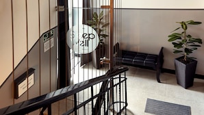 A hotel lobby with a staircase, a reception desk, and a potted plant. - SleepWell Apartments Ordynacka (Warsaw)