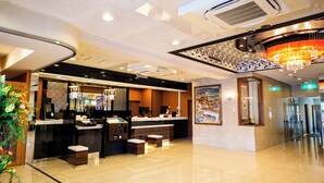 A hotel lobby with a reception desk, seating area, and a large chandelier. - APA Hotel Kochi (Kochi)