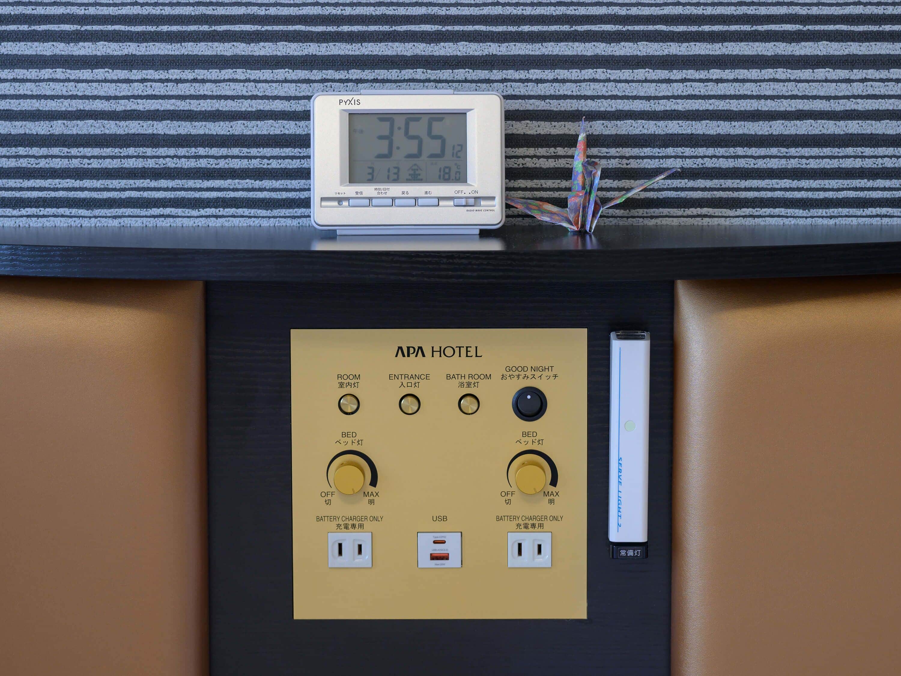 A digital clock displaying 3:55, a control panel with room and bed lighting controls, and a USB port.