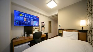 A hotel room with a bed, a desk with a computer monitor, a chair, a desk lamp, and a small refrigerator. - APA Hotel Kochi (Kochi)