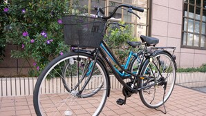 A bicycle with a basket and a seat, parked on a tiled surface. - APA Hotel Kochi (Kochi)