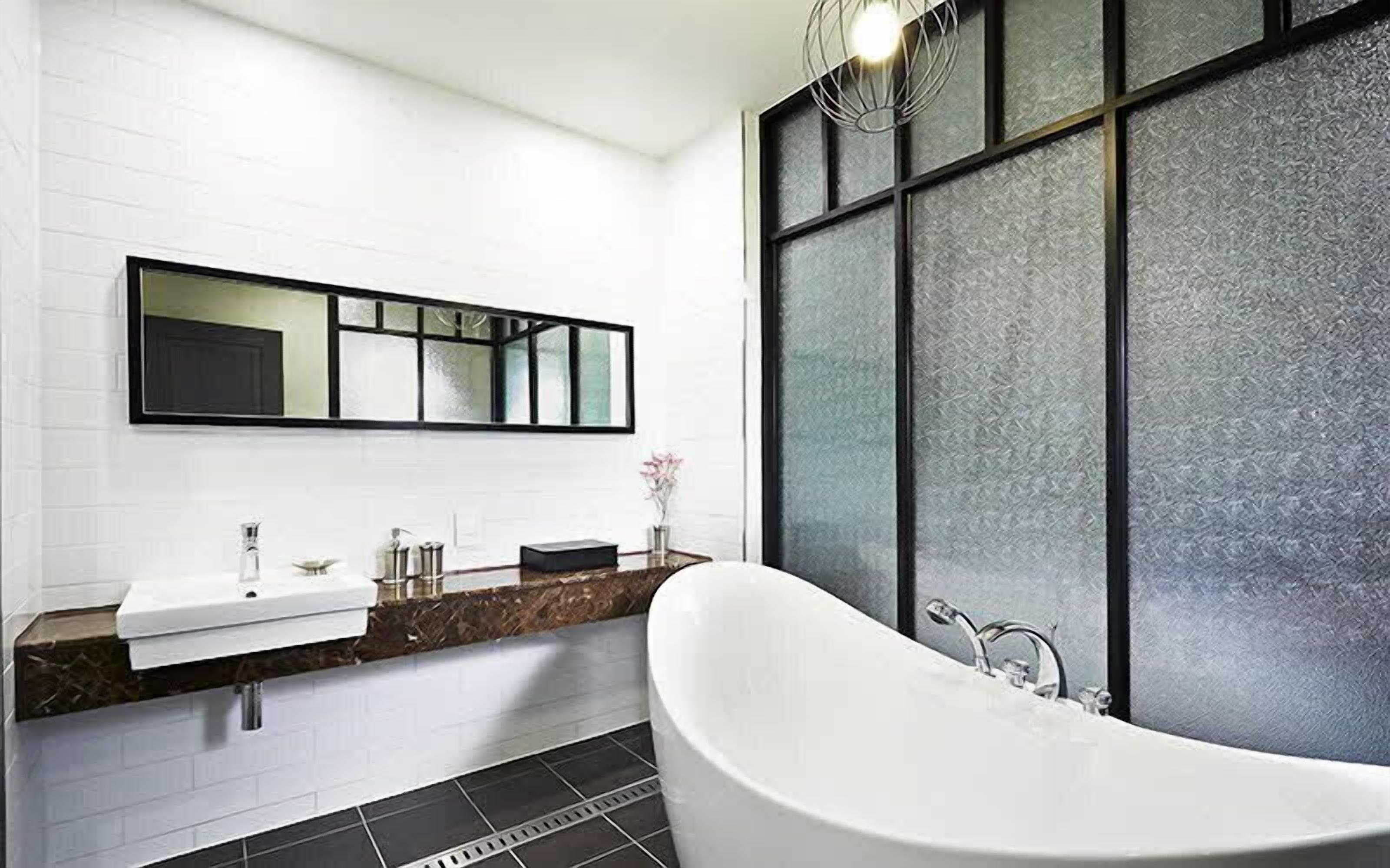 A modern bathroom with a freestanding bathtub, a large mirror, and a marble countertop.