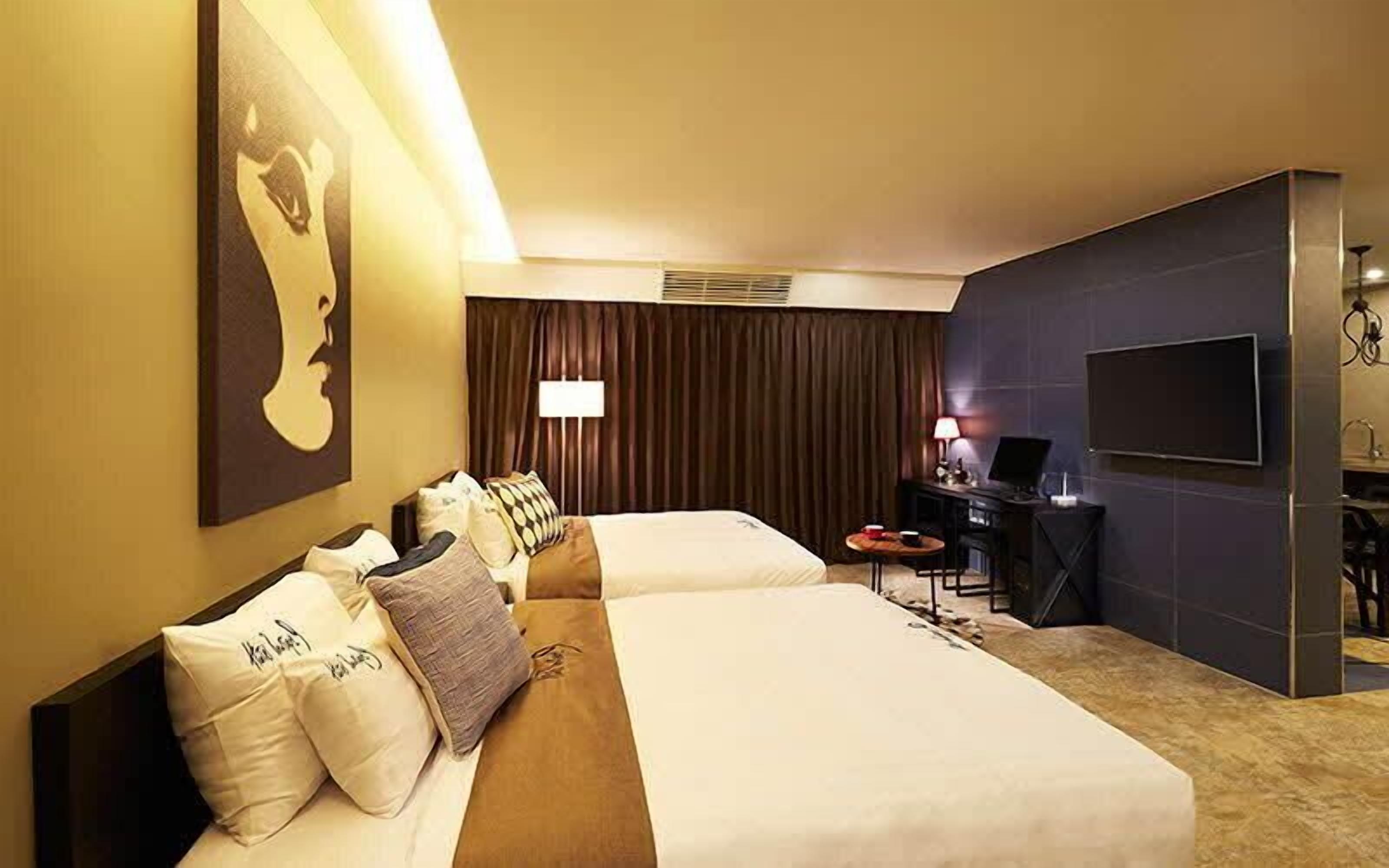 A hotel room with two beds, a desk, a TV, and a large painting on the wall.