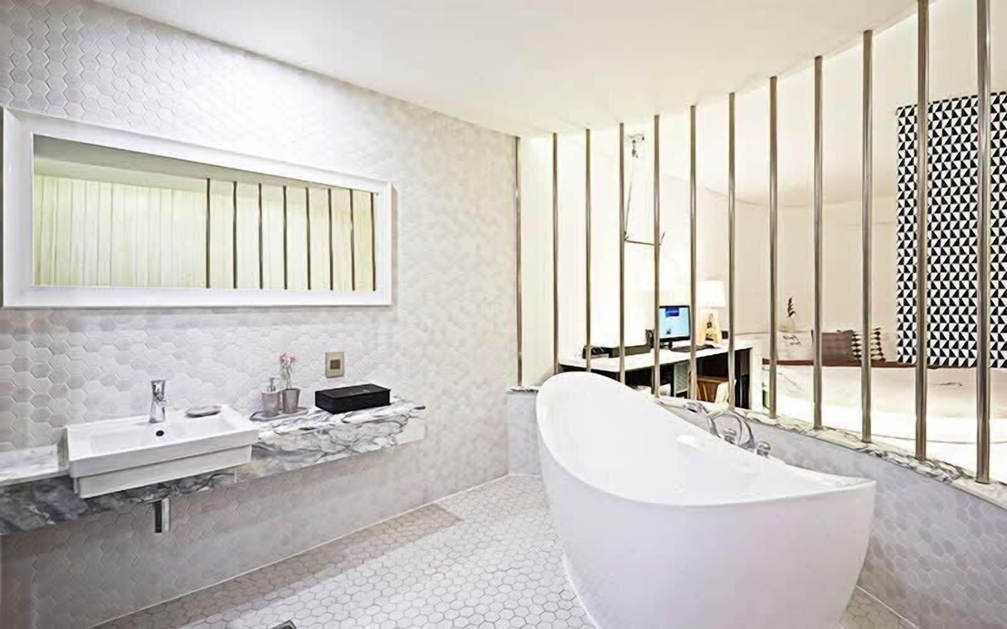 A modern bathroom with a freestanding bathtub, a large mirror, and a vanity with a sink.