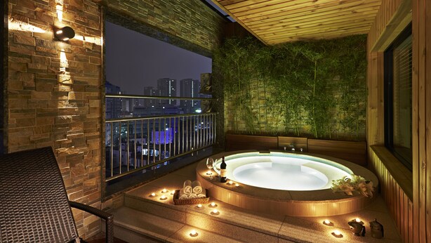 Una terraza en la azotea con hidromasaje, velas y vistas nocturnas de la ciudad.