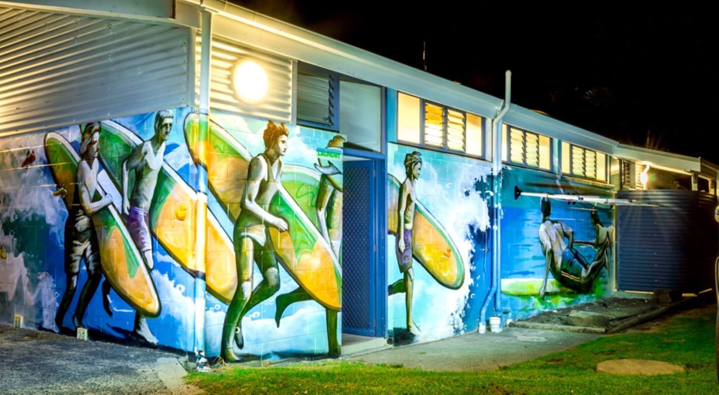 Un edificio con un mural de surfistas en la pared exterior.