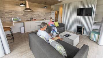 A modern living room with a grey sofa, a coffee table, and a TV mounted on a striped wall.