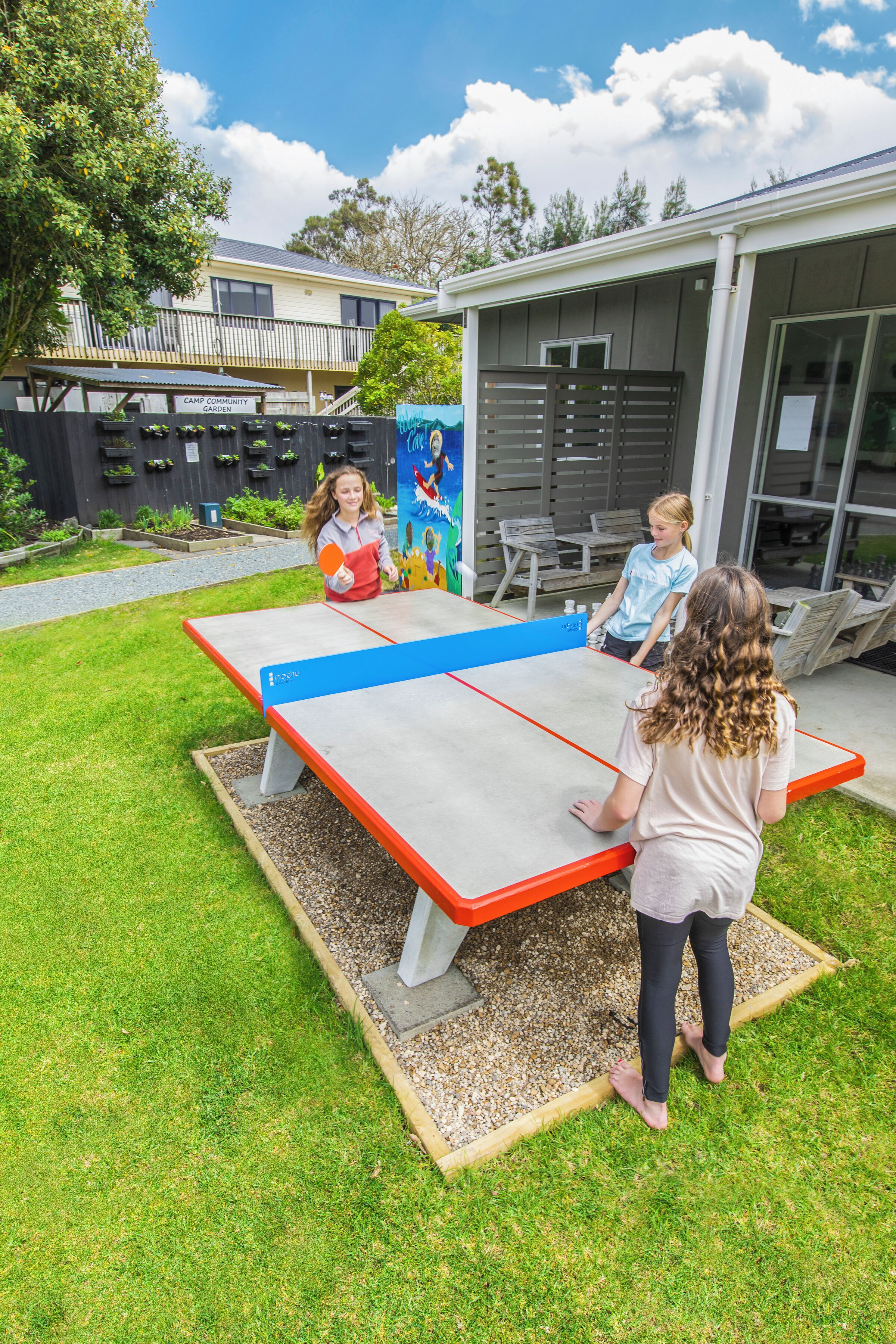 An outdoor ping pong table in a backyard with a house in the background.