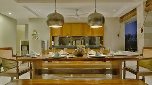 A dining area with a wooden table, chairs, and hanging pendant lights. - Villa Nikara (Canggu)
