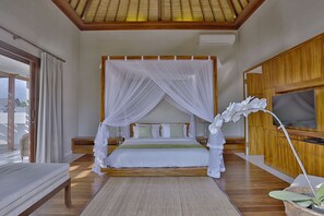 A bedroom with a canopy bed, wooden flooring, a flat-screen TV, and a large window.