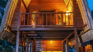 A thatched-roof building with a wooden deck and a staircase leading to a balcony. - Sukanusa Luxury Huts (Lembongan Island)