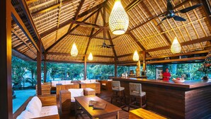 A restaurant with wooden furniture, a bar, and a thatched roof. - Sukanusa Luxury Huts (Lembongan Island)