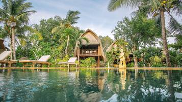 Una piscina al aire libre, sombrillas, sillones reclinables de piscina