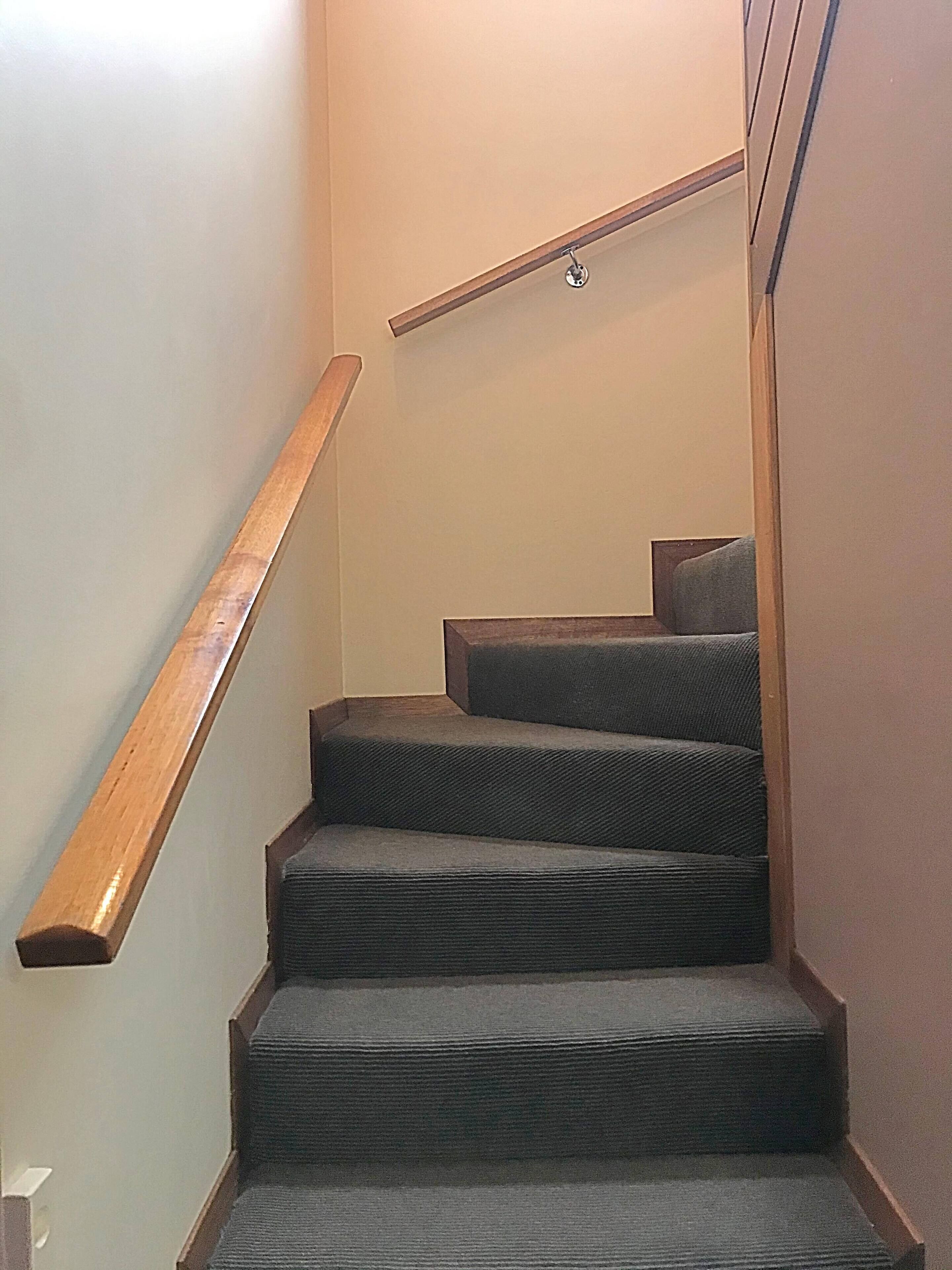 A staircase with wooden handrails and carpeted steps.