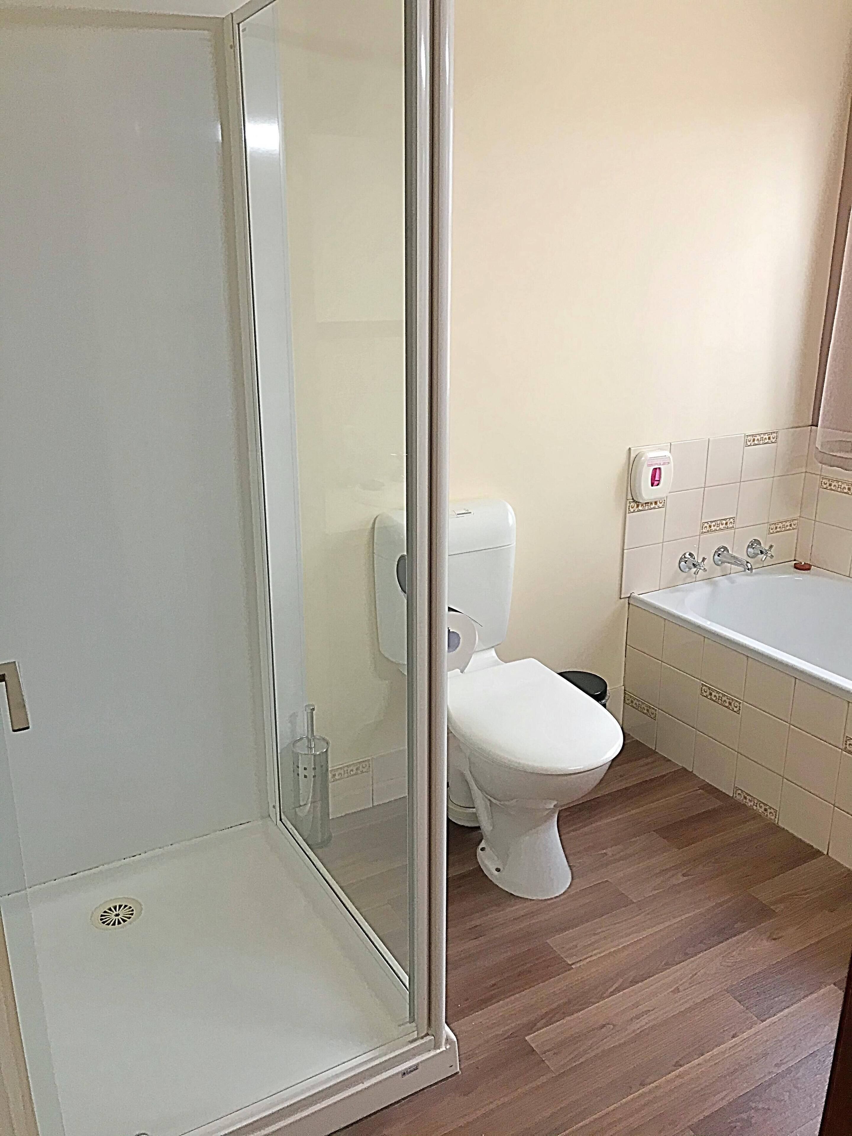 A bathroom with a glass shower enclosure, a toilet, and a bathtub.