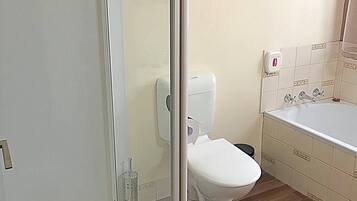A bathroom with a glass shower enclosure, a toilet, and a bathtub.
