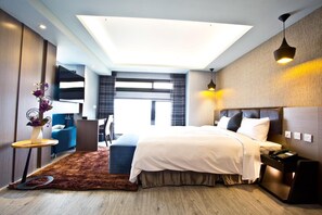 A modern hotel room with a large bed, a desk, a chair, and a view of the city. - Fine Hotel (Kaohsiung)