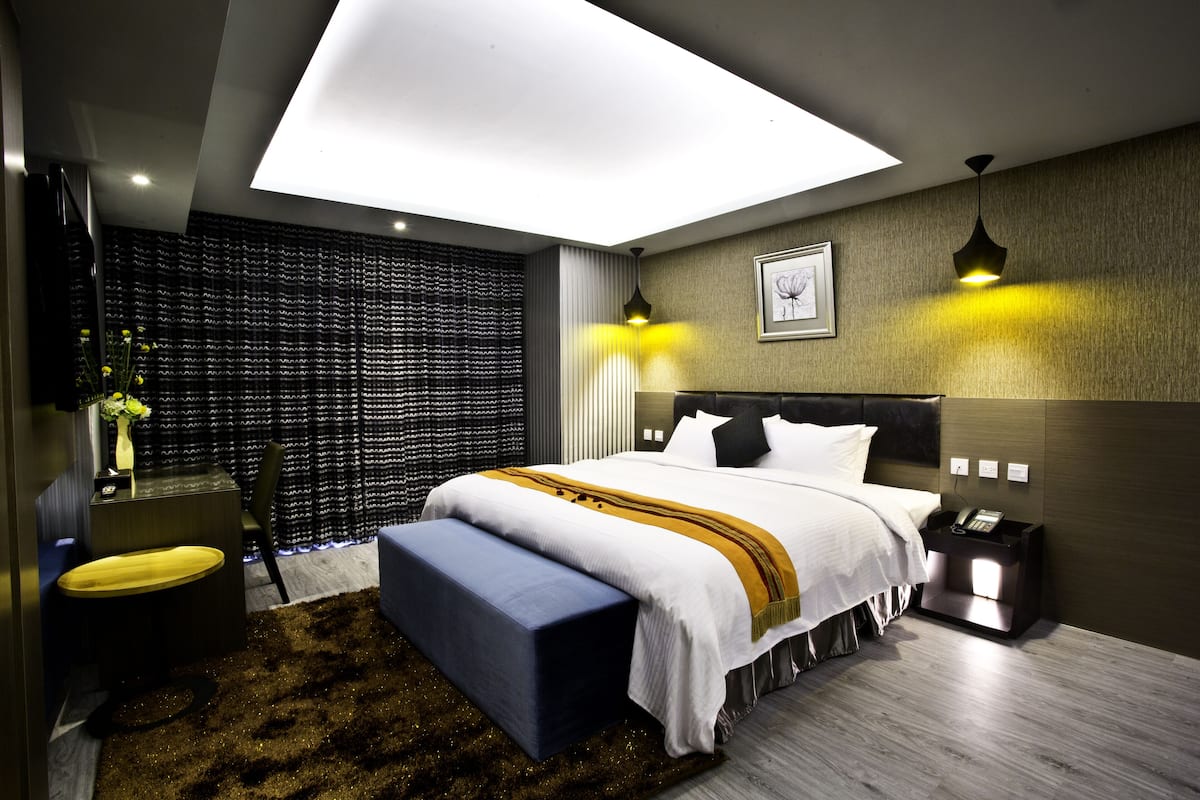 A modern hotel room with a large bed, bedside lamps, a desk, and a view through the window.