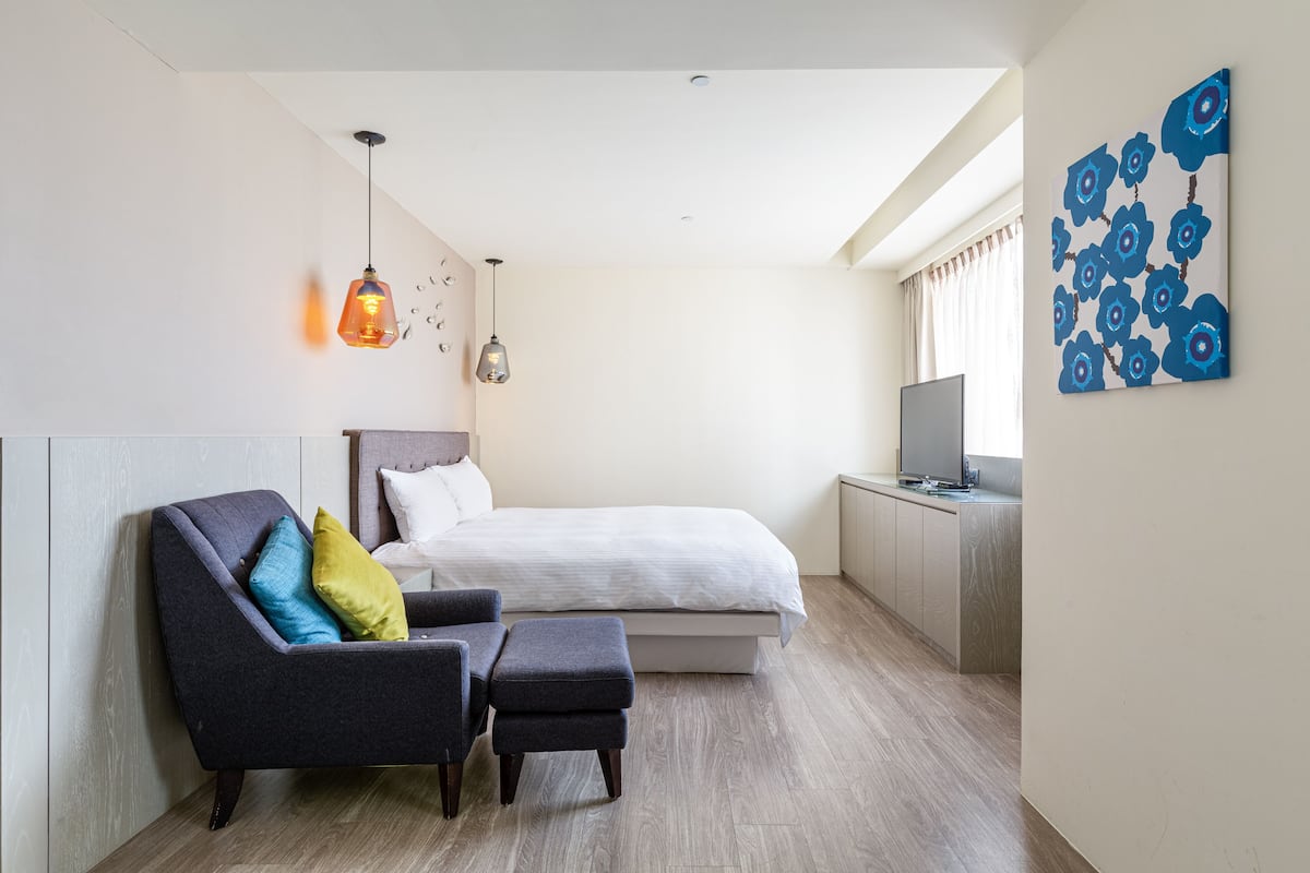 Une chambre moderne avec un lit, un bureau, une chaise et un téléviseur.