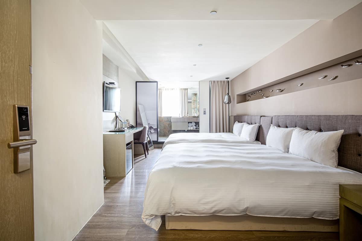 Une chambre d’hôtel moderne, dotée d’un grand lit, d’un bureau et offrant une vue sur la ville.
