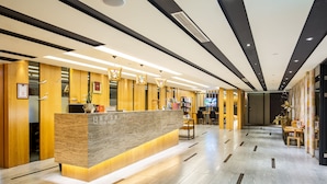 Un espace d’accueil moderne, avec un comptoir en marbre, des éléments décoratifs en bois et un intérieur épuré et bien éclairé.