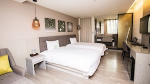 Une chambre d’hôtel avec deux lits, un bureau, une chaise et un téléviseur.
