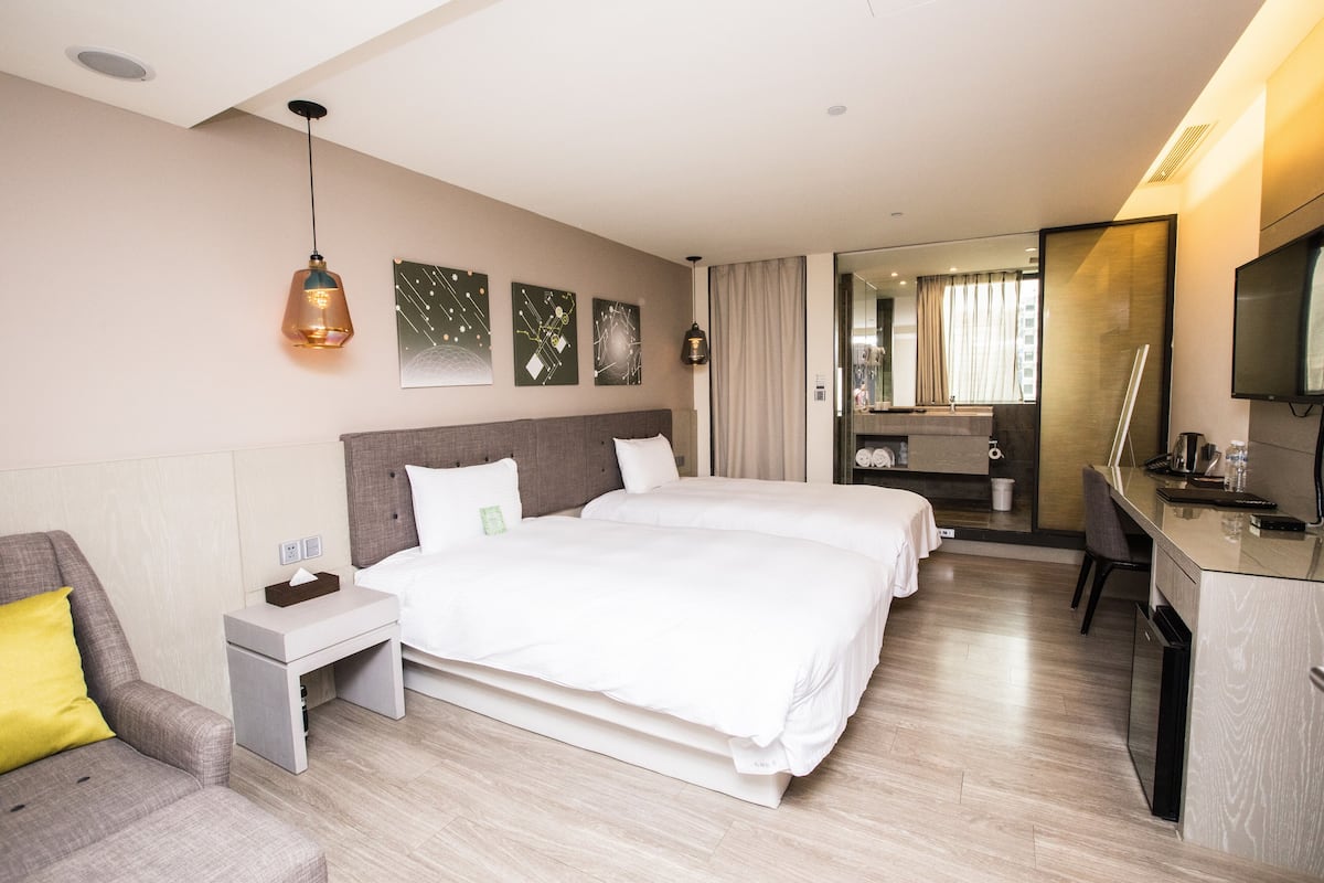 Une chambre d’hôtel avec deux lits, un bureau, une chaise et un téléviseur.