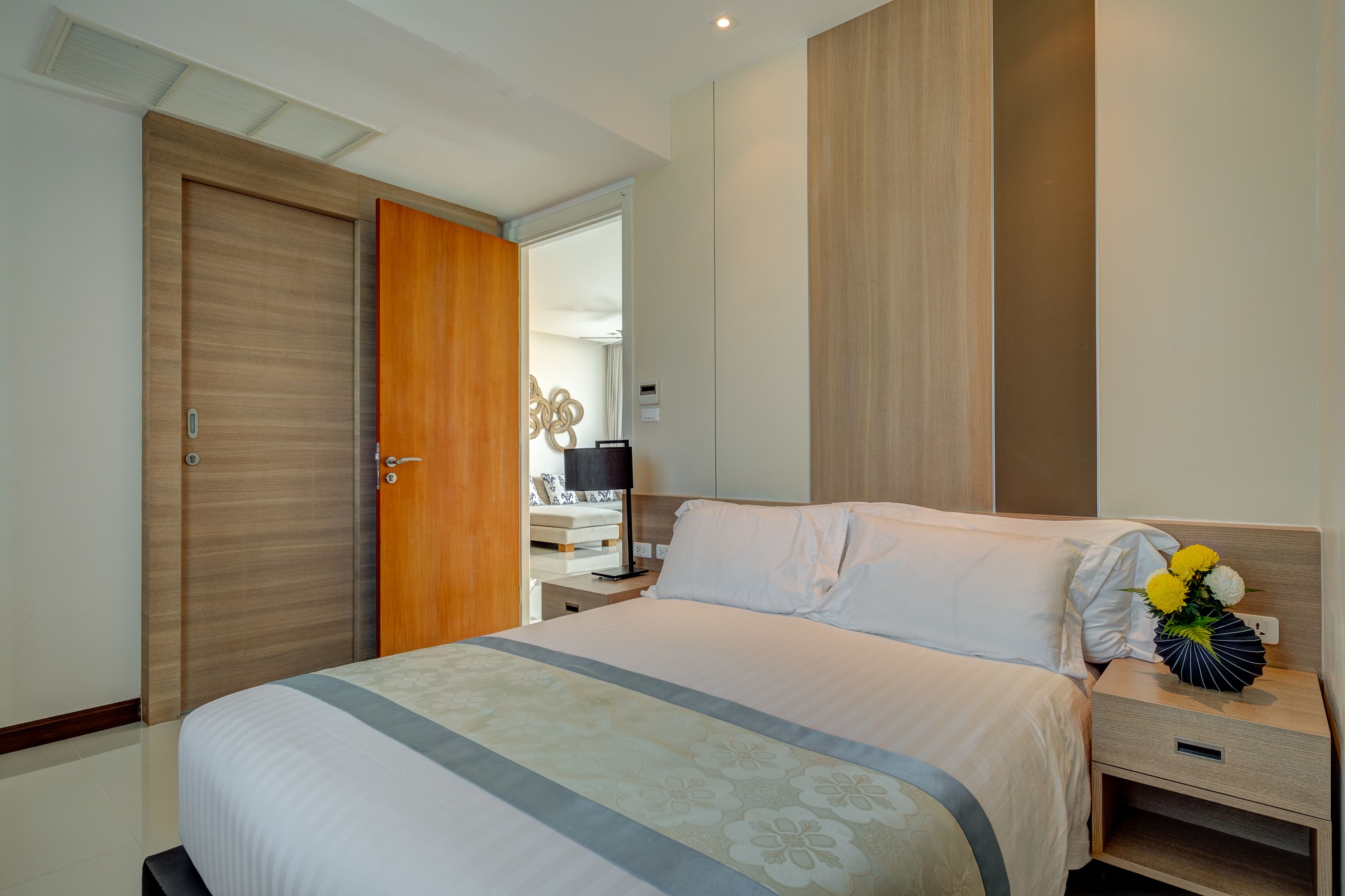 A hotel room with a bed, a nightstand, a lamp, and a wall-mounted shelf.