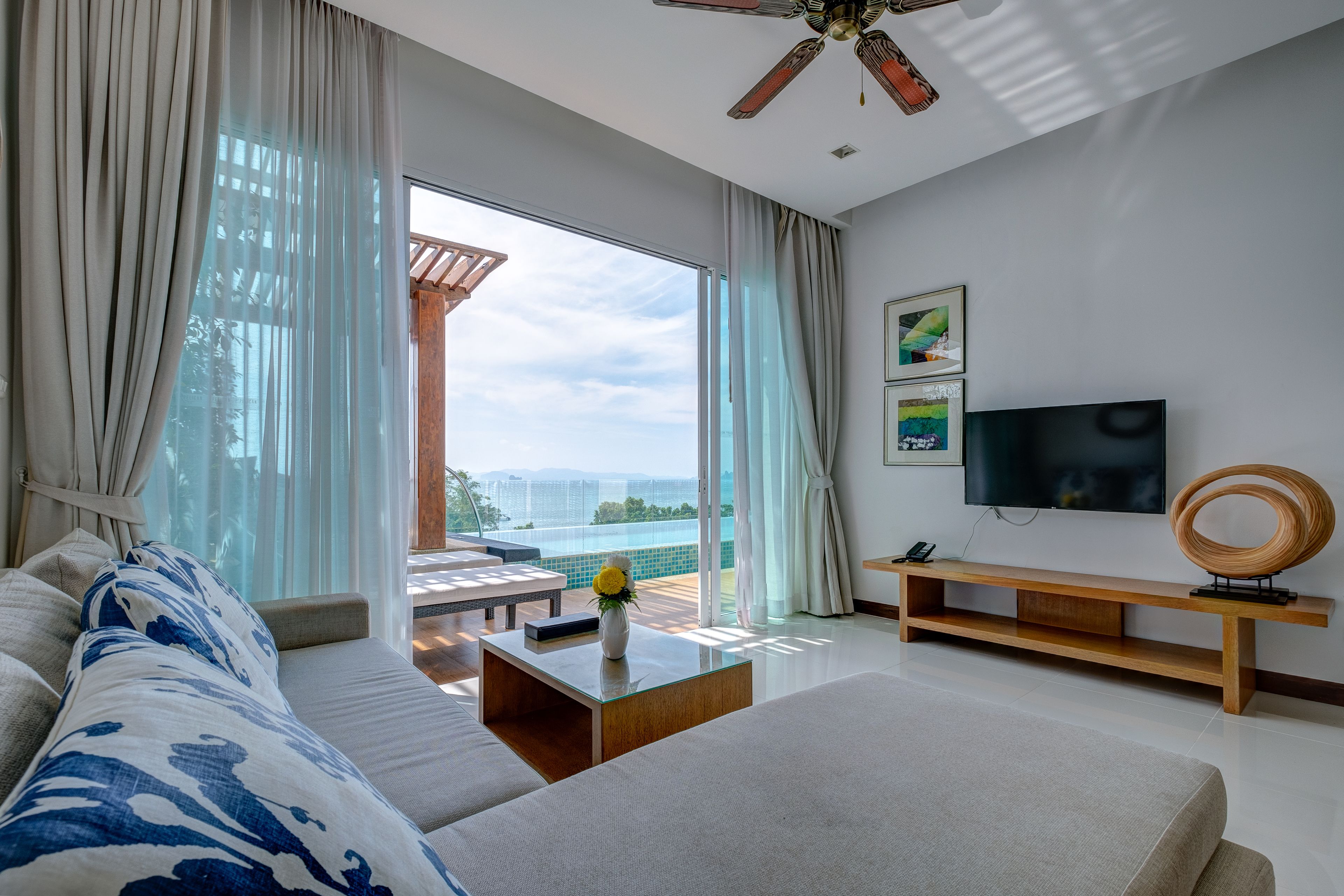 Quarto de hotel moderno com uma cama grande, um sofá, uma mesa de centro, TV e varanda com vista para a cidade.