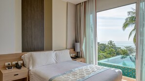 A modern hotel room with a large bed, a bedside table, a lamp, and a view of a pool and palm trees. - The Pelican Residence & Suite Krabi (Krabi)