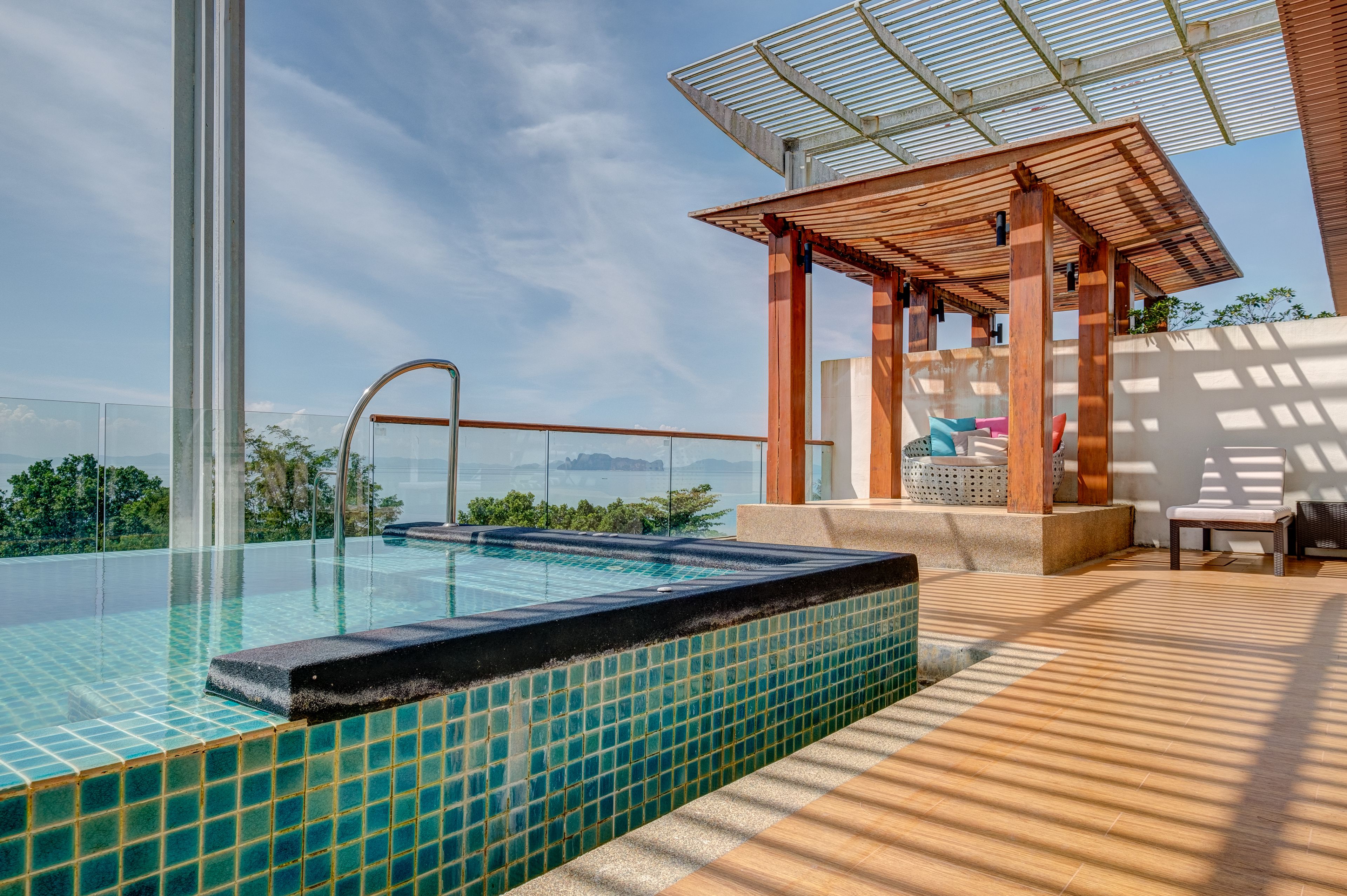 Una piscina infinita en la azotea con terraza de madera y pérgola.