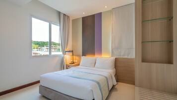 Un dormitorio moderno con una cama grande, una mesita de noche, una ventana con cortinas y vistas a espacios verdes.