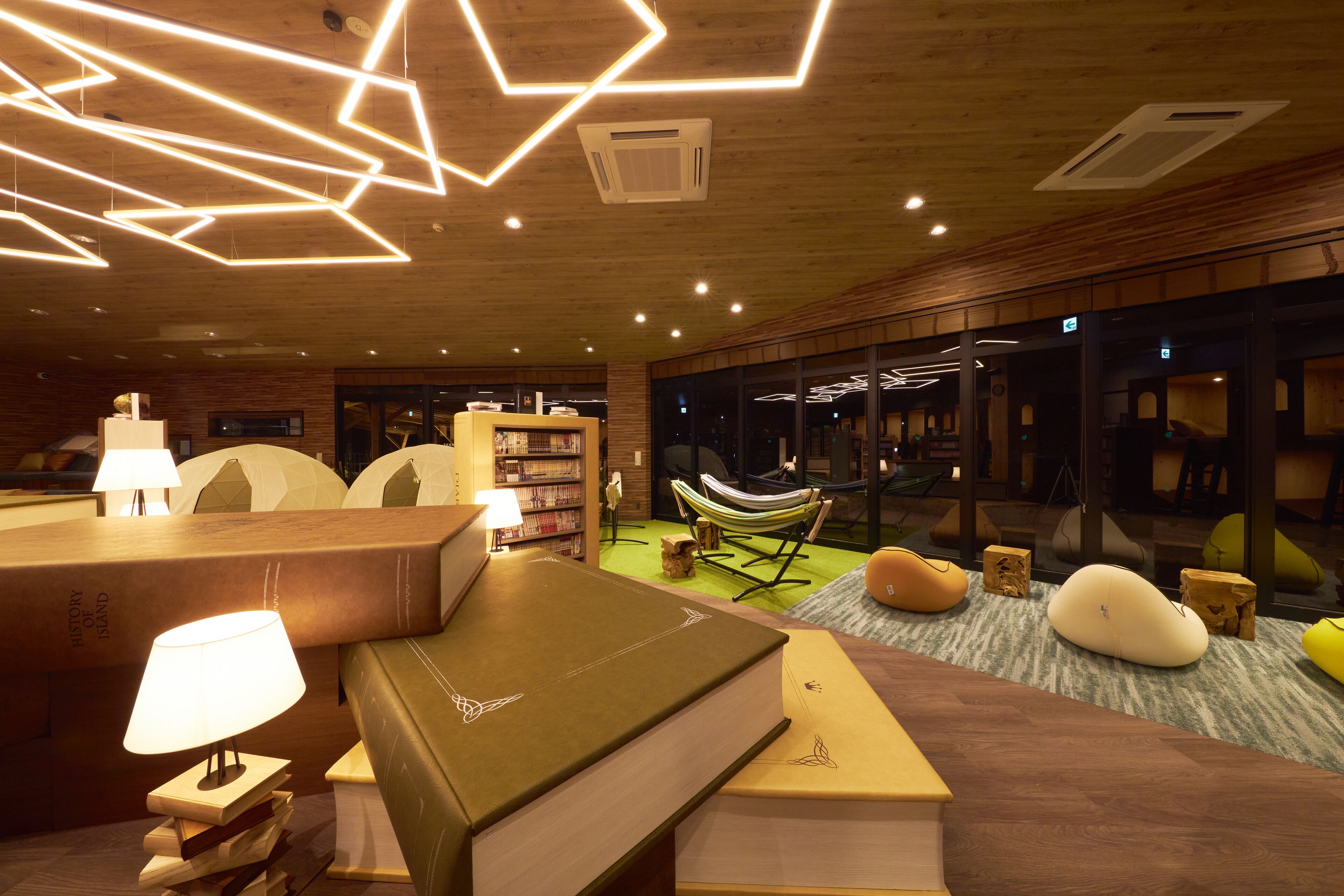 A cozy reading area with books, a lamp, and a hammock.