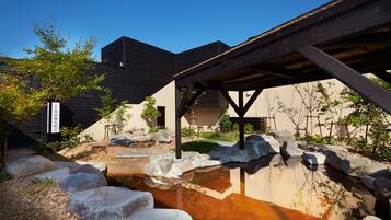 Traditional Japanese-style building surrounded by serene natural landscape and a small pond.