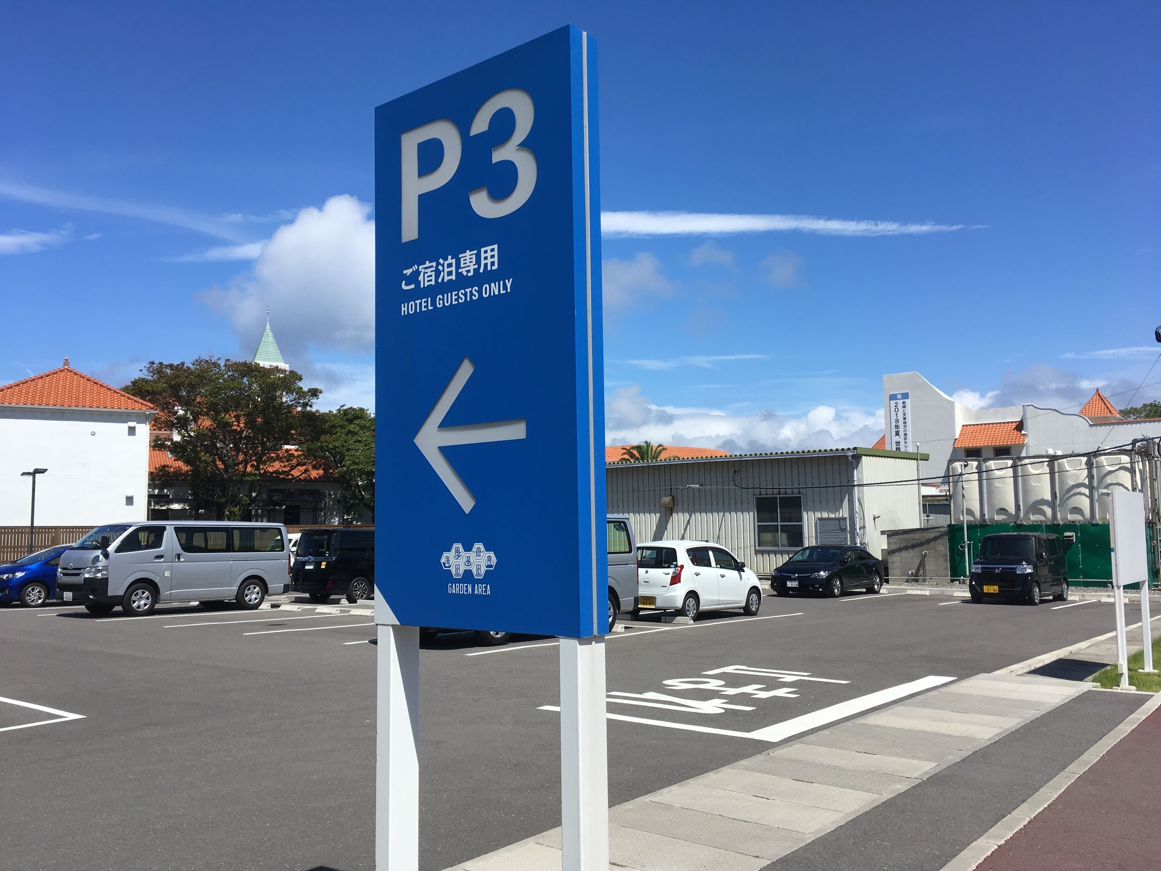 A blue parking sign with an arrow pointing left, indicating the direction for hotel guests.