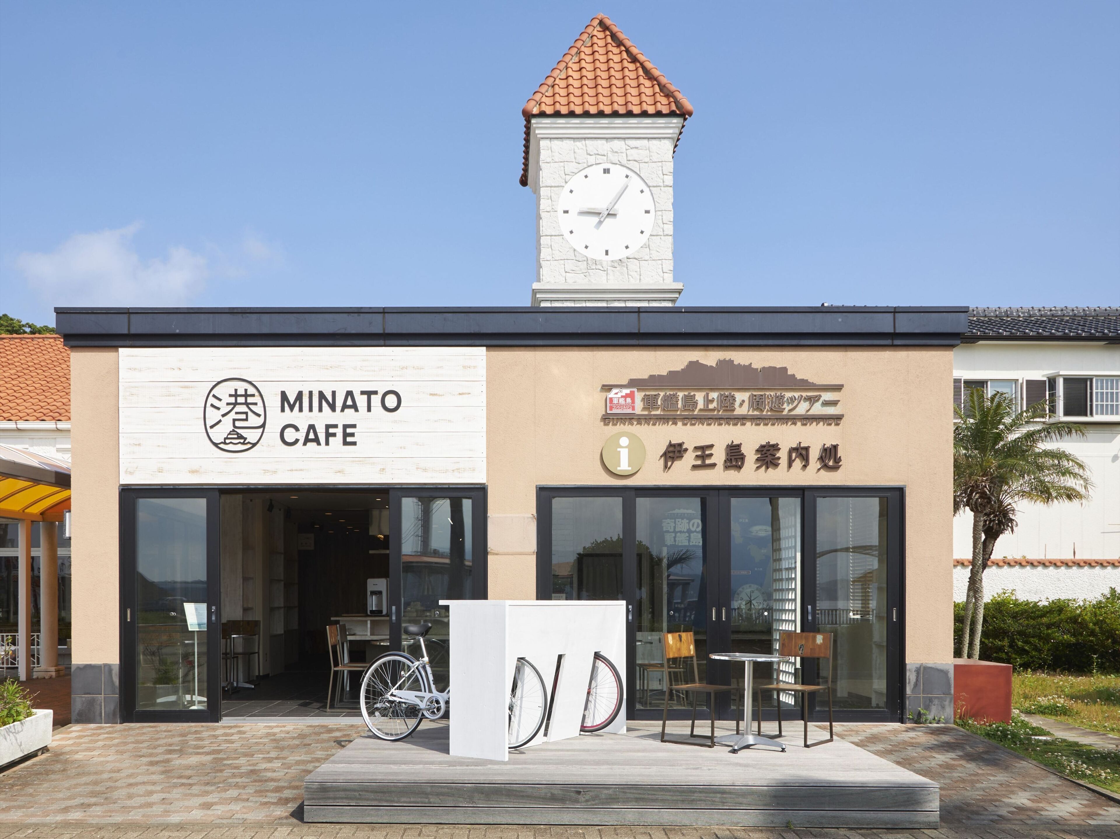 A cafe with a clock tower, outdoor seating, and a bicycle parked outside.