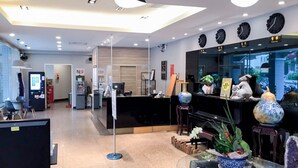 Een moderne receptie met een glazen bureau, een zwarte balie en een klok aan de muur.