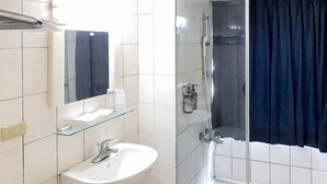 Een badkamer met een witte wastafel, een glazen douchecabine en een donkerblauwe douchegordijn.