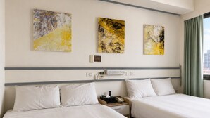 Een hotelkamer met twee bedden, een nachtkastje, een telefoon en abstracte kunst aan de muur.